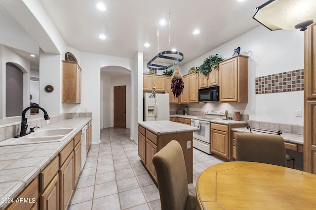 kitchen featuring a sink, tile countertops, a center island, white appliances, and arched walkways