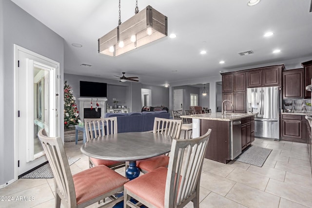 tiled dining room with ceiling fan and sink