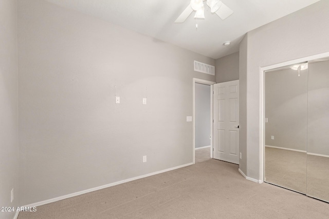 unfurnished bedroom featuring ceiling fan, light carpet, and a closet