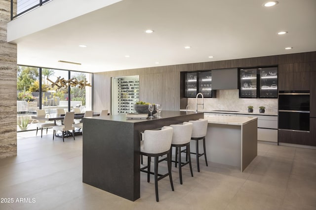 4451 E Joshua Tree Ln, Paradise Valley, AZ 85253 - kitchen featuring modern cabinets, a large island, a kitchen bar, recessed lighting, and glass insert cabinets