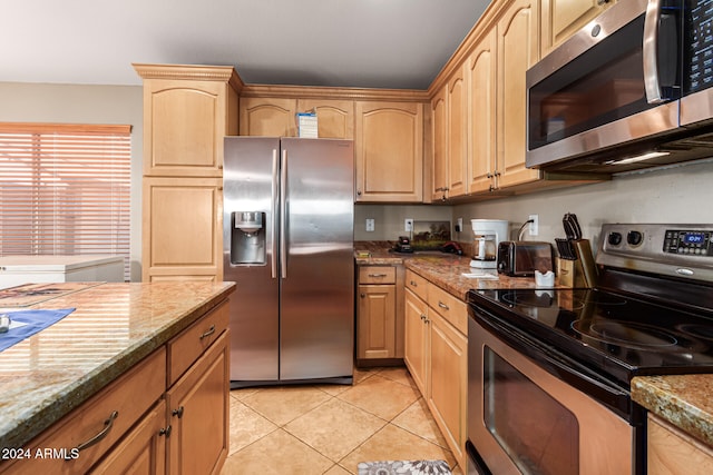 kitchen featuring light brown cabinets, light tile patterned floors, light stone countertops, and appliances with stainless steel finishes