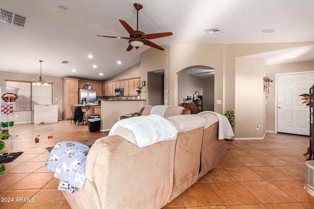 living room with ceiling fan with notable chandelier, light tile patterned flooring, and lofted ceiling