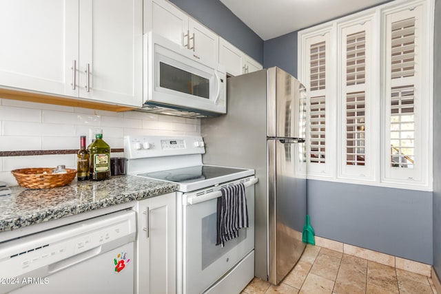 kitchen with white cabinets, stone countertops, white appliances, decorative backsplash, and light tile patterned floors