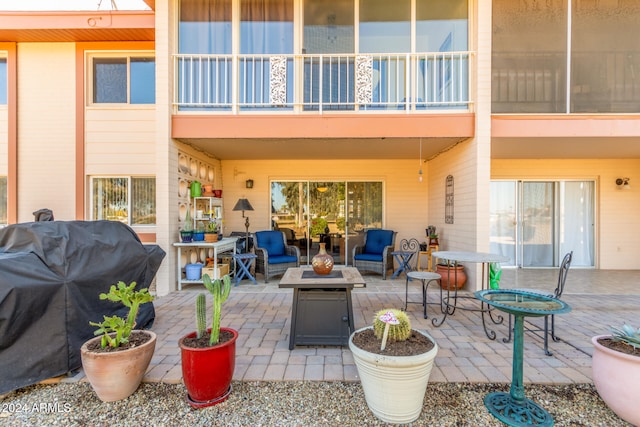 view of patio / terrace with a grill, a balcony, and an outdoor living space with a fire pit