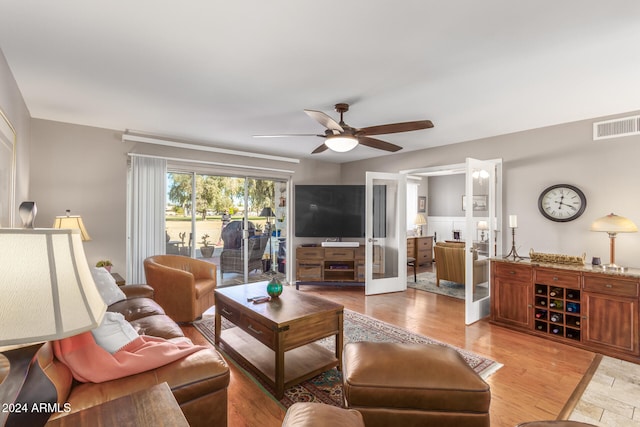 living room featuring ceiling fan, light hardwood / wood-style floors, and french doors