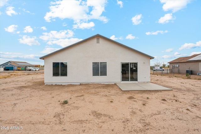 rear view of property featuring stucco siding, fence, cooling unit, and a patio