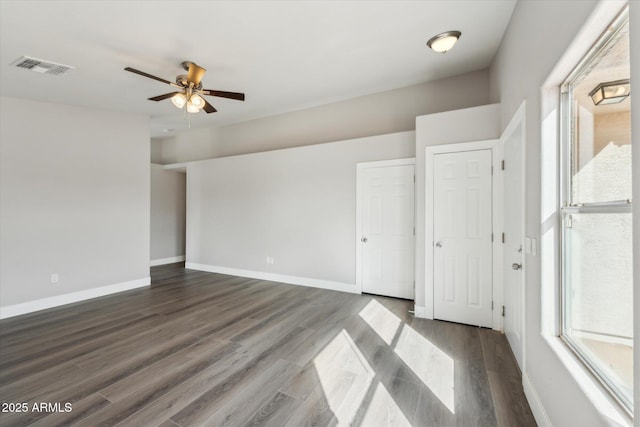 empty room with a ceiling fan, baseboards, visible vents, and dark wood-style flooring