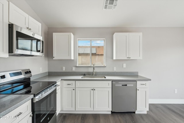 kitchen featuring visible vents, white cabinets, dark wood-type flooring, stainless steel appliances, and a sink