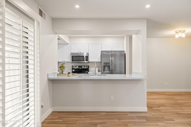 kitchen with sink, light hardwood / wood-style flooring, stainless steel appliances, and white cabinets