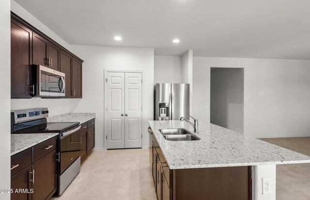 5053 S 252nd Ave, Buckeye, AZ 85326 - kitchen with dark brown cabinets, appliances with stainless steel finishes, an island with sink, a sink, and light stone counters