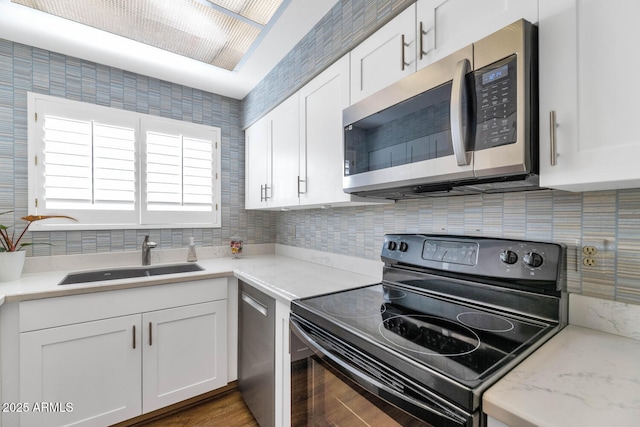 kitchen with backsplash, sink, white cabinetry, and stainless steel appliances