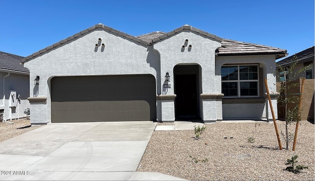 french country inspired facade featuring a garage, driveway, a tile roof, and stucco siding