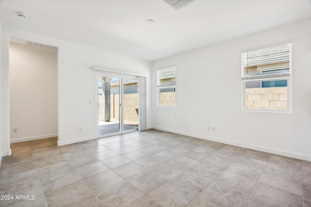 empty room featuring light tile patterned floors, baseboards, and visible vents