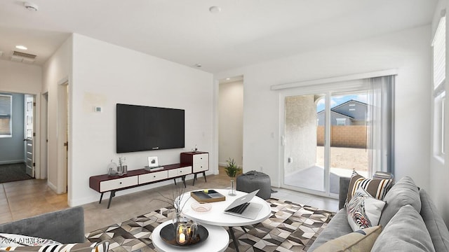 living area featuring light carpet, light tile patterned flooring, visible vents, and baseboards