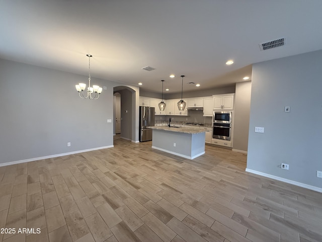 kitchen featuring stainless steel appliances, arched walkways, visible vents, and a sink