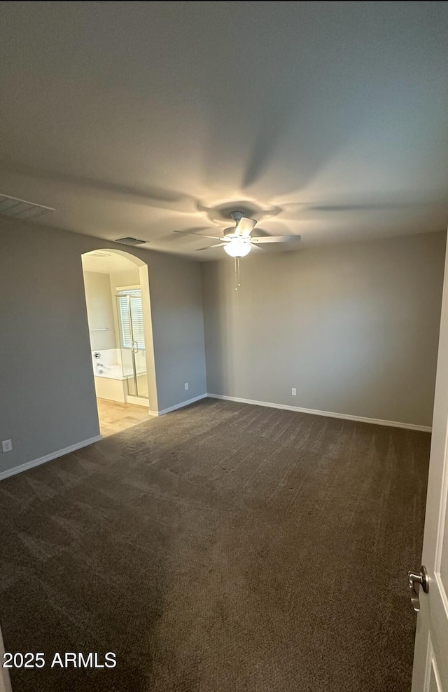 spare room with arched walkways, light colored carpet, baseboards, and ceiling fan