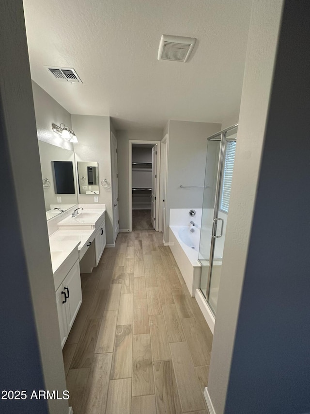 full bath featuring a shower stall, visible vents, a textured ceiling, and wood finished floors