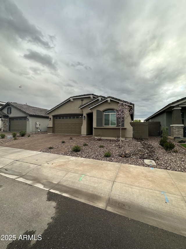 view of front of home with concrete driveway, an attached garage, fence, and stucco siding