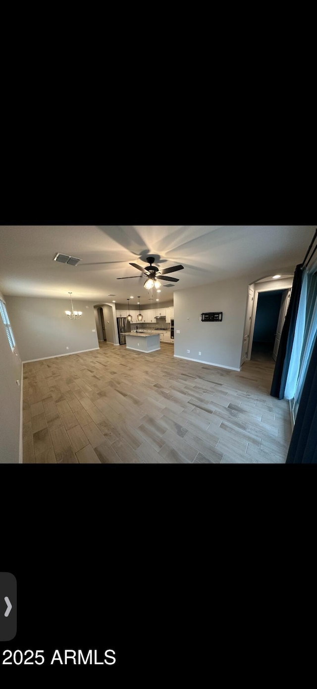 unfurnished living room featuring visible vents, a ceiling fan, and light wood-style flooring
