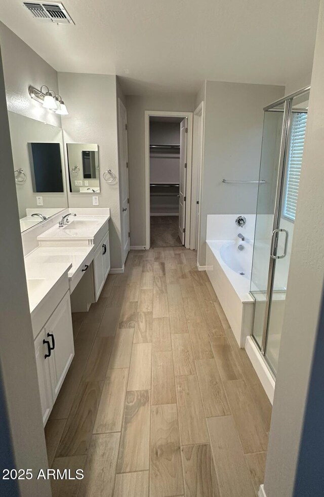 bathroom with a stall shower, wood finished floors, vanity, and visible vents