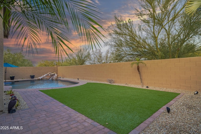 yard at dusk featuring a fenced in pool and pool water feature