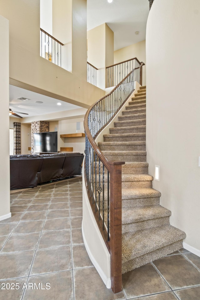 staircase with ceiling fan, tile patterned flooring, and a high ceiling