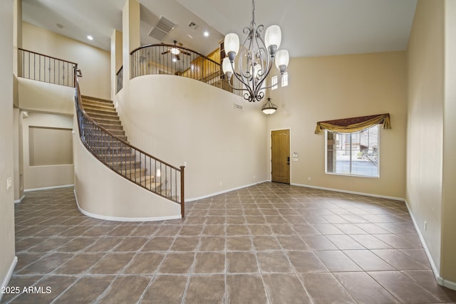 tiled foyer featuring ceiling fan with notable chandelier and a high ceiling