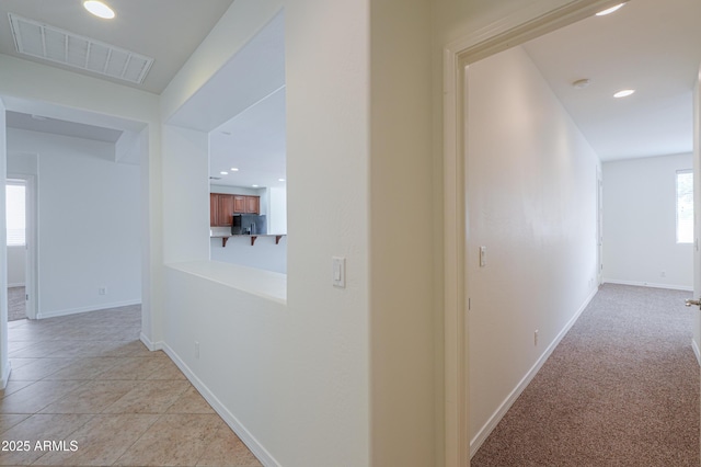 hall with light tile patterned flooring, recessed lighting, visible vents, and baseboards