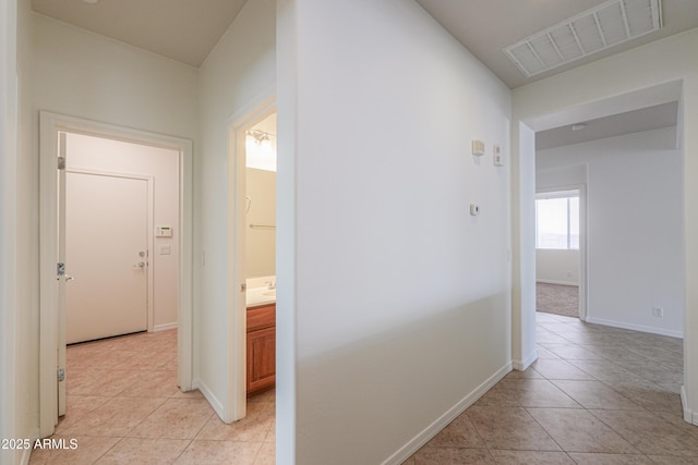 corridor featuring light tile patterned floors, visible vents, and baseboards