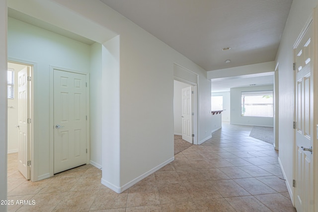 hallway with light tile patterned floors and baseboards