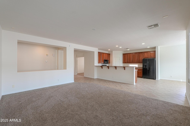 unfurnished living room with light carpet, light tile patterned floors, visible vents, and recessed lighting