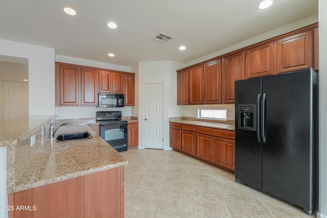 kitchen with visible vents, a sink, light stone countertops, a peninsula, and black appliances