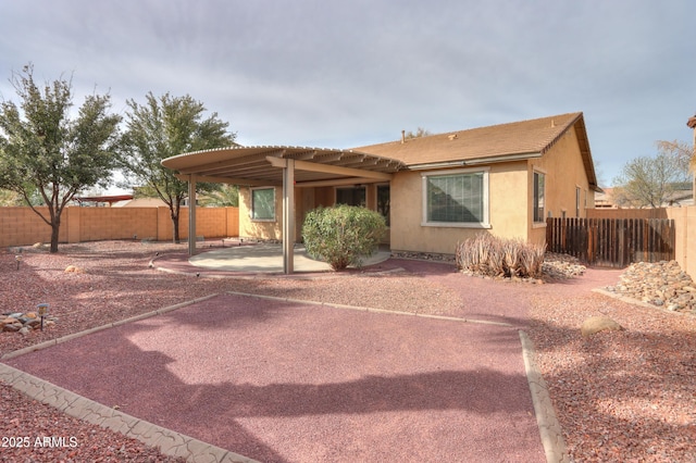 view of front of home featuring a pergola, a fenced backyard, a patio, and stucco siding