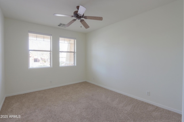 empty room featuring ceiling fan, carpet floors, visible vents, and baseboards