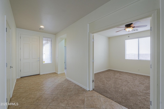 foyer featuring light tile patterned flooring, visible vents, baseboards, and light colored carpet