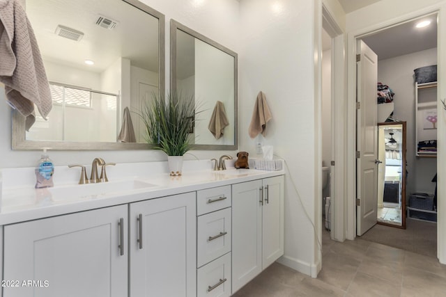 bathroom featuring tile patterned flooring, vanity, toilet, and an enclosed shower