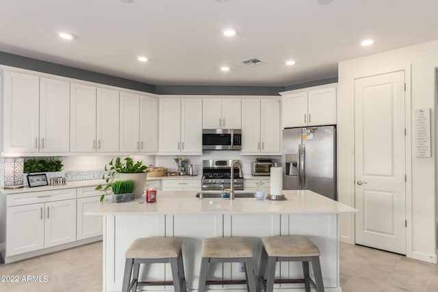 kitchen featuring an island with sink, stainless steel appliances, white cabinetry, and sink