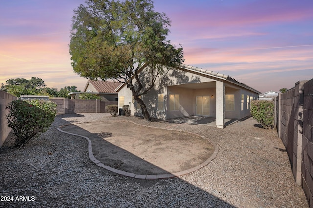 back house at dusk featuring a patio