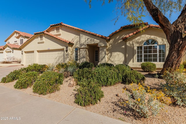 mediterranean / spanish home featuring a tiled roof, an attached garage, driveway, and stucco siding