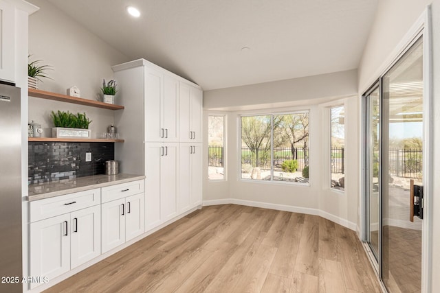 interior space featuring open shelves, freestanding refrigerator, white cabinetry, light wood-type flooring, and baseboards