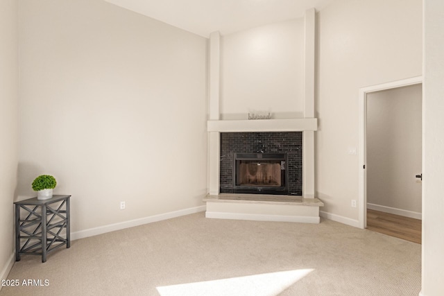 unfurnished living room with baseboards, carpet flooring, and a tiled fireplace