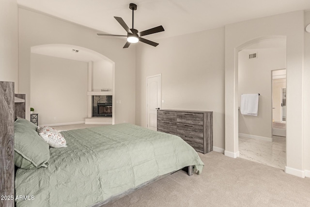 bedroom with visible vents, a glass covered fireplace, carpet flooring, ceiling fan, and baseboards