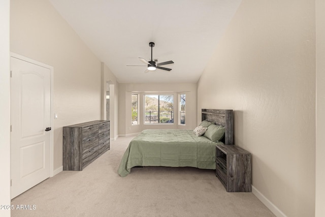 bedroom featuring light carpet, vaulted ceiling, baseboards, and ceiling fan