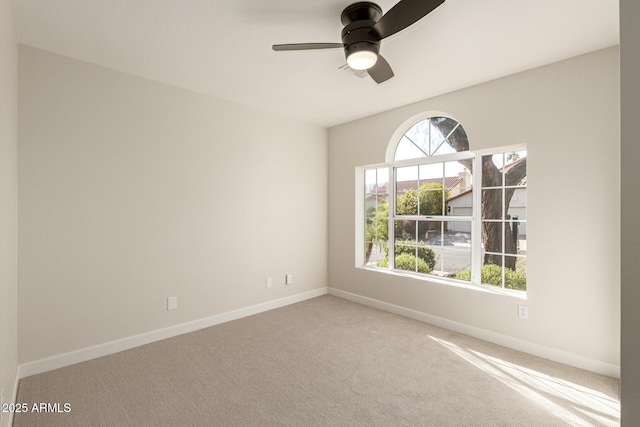 carpeted empty room featuring a ceiling fan and baseboards