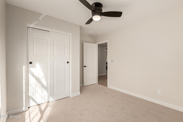 unfurnished bedroom featuring ceiling fan, a closet, carpet, and baseboards