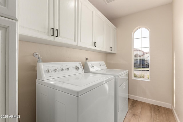 clothes washing area featuring light wood-style flooring, independent washer and dryer, cabinet space, and baseboards