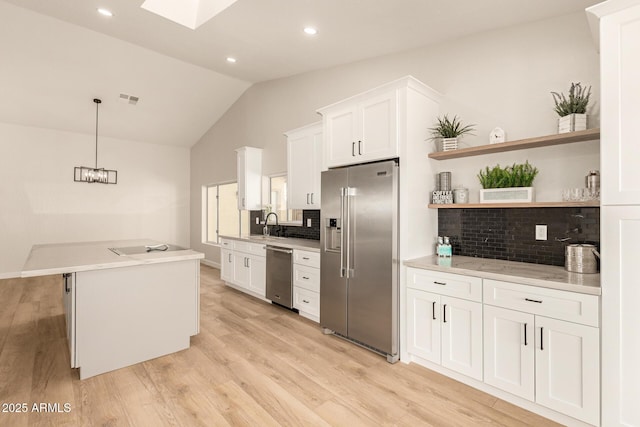 kitchen featuring appliances with stainless steel finishes, vaulted ceiling with skylight, visible vents, and light wood finished floors