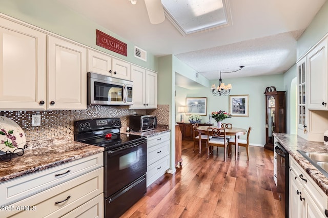 kitchen with decorative light fixtures, tasteful backsplash, white cabinets, hardwood / wood-style flooring, and black appliances