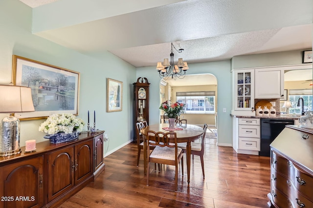 dining room with sink, a textured ceiling, a notable chandelier, and dark hardwood / wood-style flooring