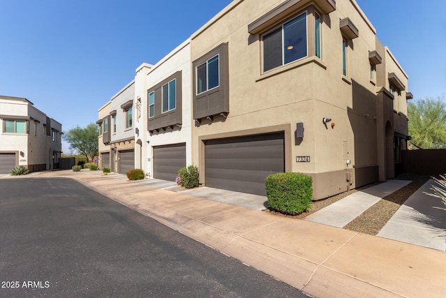 view of front of home with a garage, a residential view, and stucco siding